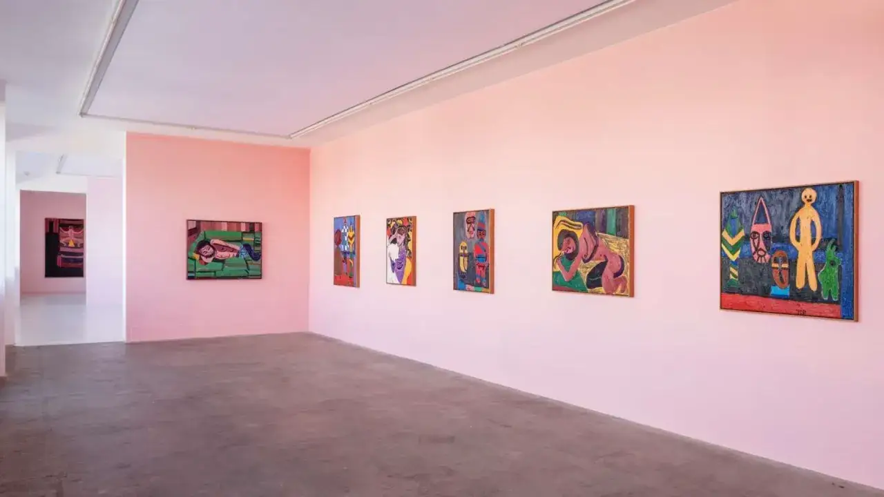 Vibrant paintings adorn the pink walls of Copenhagen art galleries, showcasing bold figures and abstract designs.