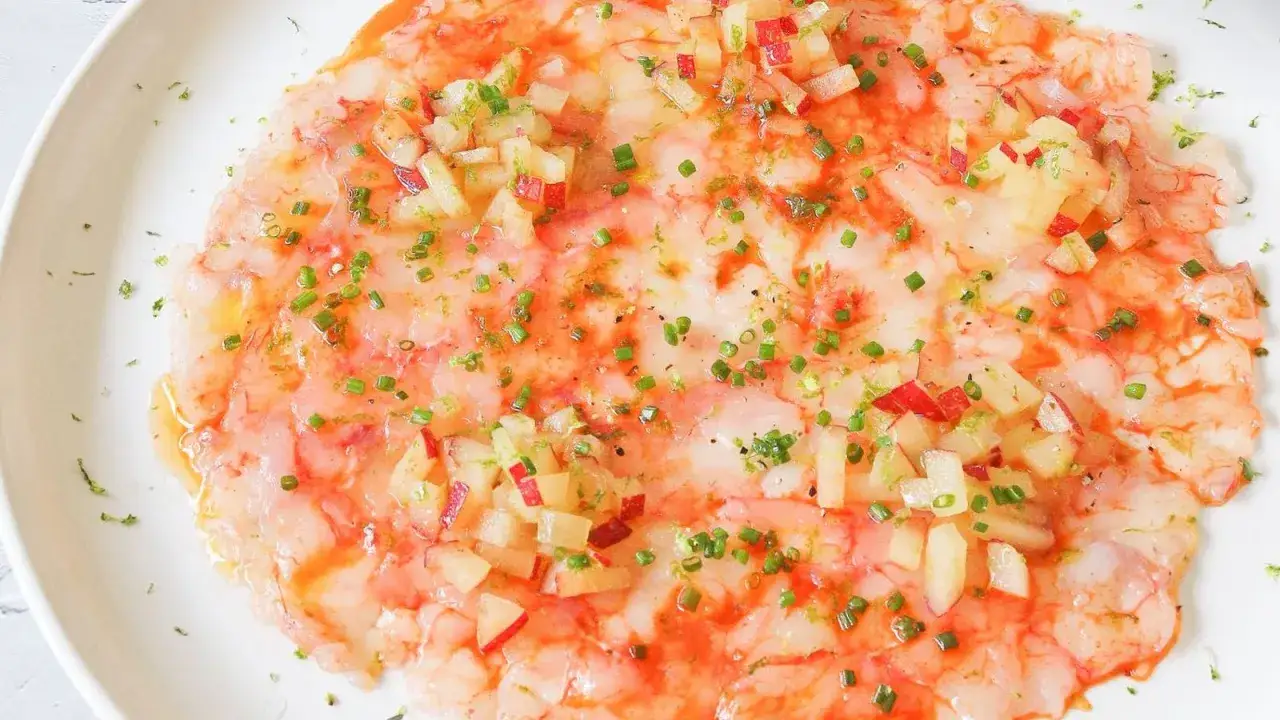 Delicioso carpaccio de gambas con trocitos de manzana, cebollino y ralladura de lima. Un plato fresco y vibrante.