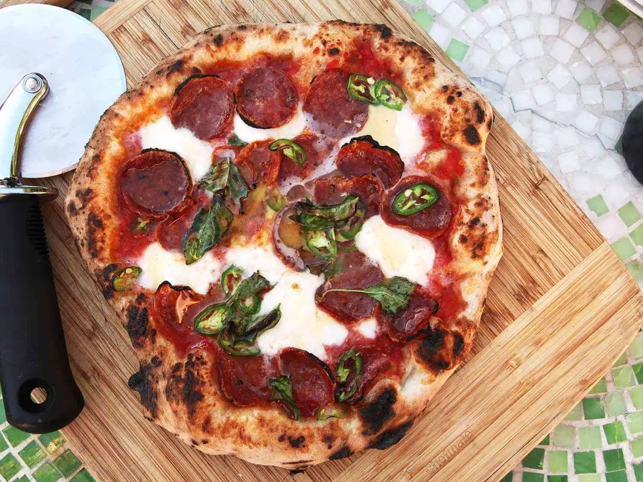 Pikantna pizza diavola z pikantnym salami, mozzarellą i papryczkami jalapeño, gotowa do pokrojenia.