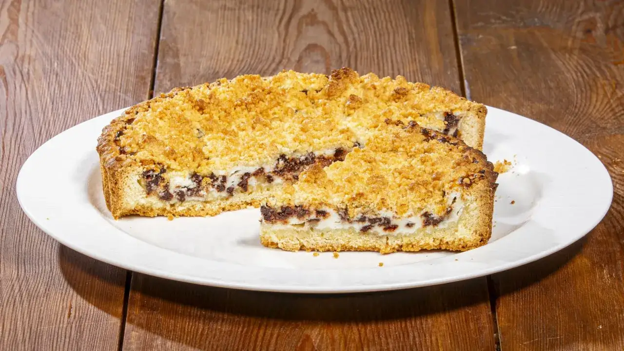 Sbriciolata ricotta e cioccolato: una fetta di torta con crosta dorata e ripieno cremoso di ricotta e gocce di cioccolato fondente.