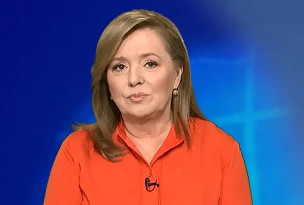 Danuta Holecka w pomarańczowej bluzce, z fryzurą i makijażem sugerującym zabiegi, jak operacje plastyczne.