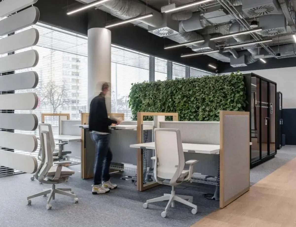 Un bureau moderne avec des postes de travail &eacute;pur&eacute;s, des cloisons acoustiques et un mur v&eacute;g&eacute;tal luxuriant. Ces plantes de bureau apportent une touche de nature et de fra&icirc;cheur &agrave; l'espace.