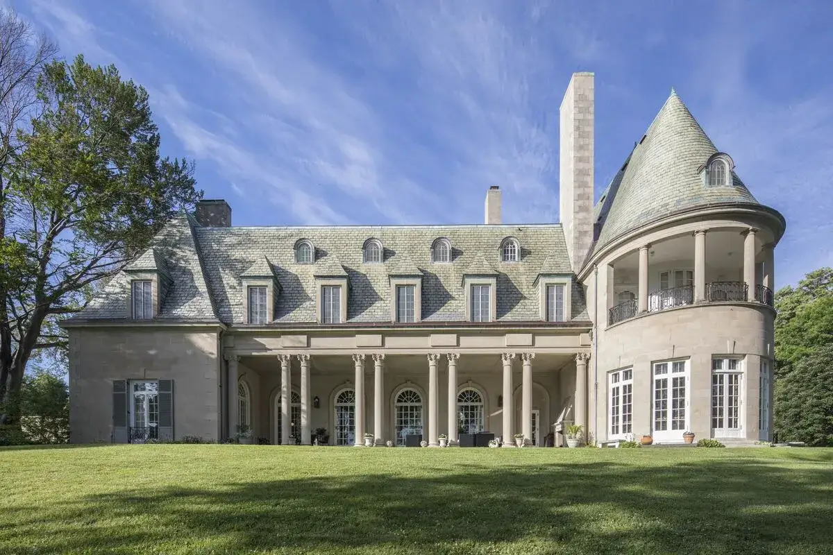 La maestosa villa, sfondo ideale per il grande Gatsby trama, si staglia sotto un cielo azzurro con nuvole sottili.