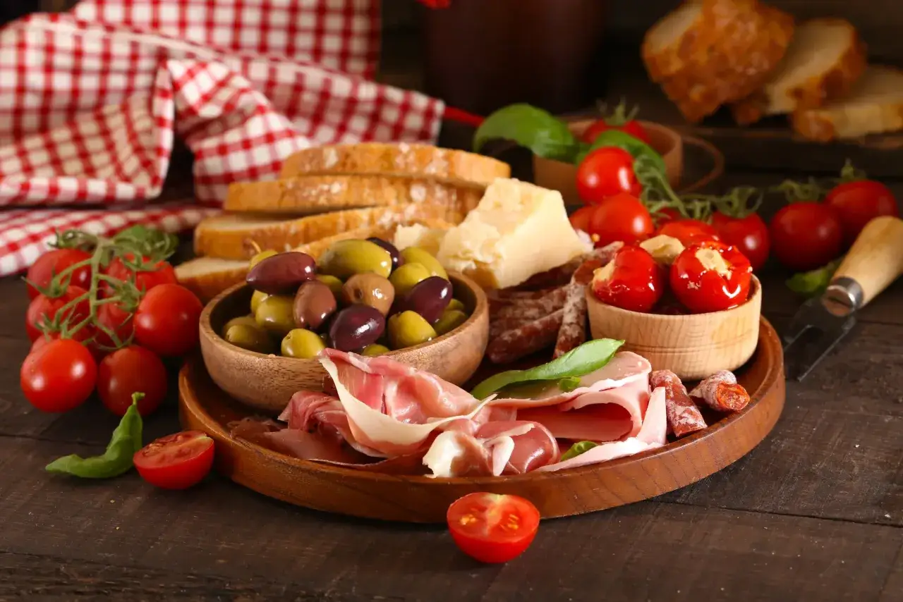 Deska serów i wędlin z pomidorkami, oliwkami, chlebem i plasterkami **salami napoli**.