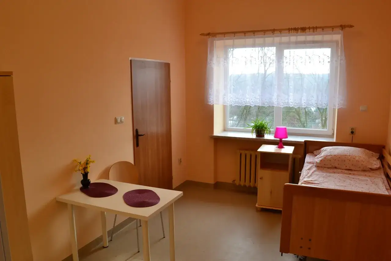 Elegancki budynek domu opieki w otoczeniu zieleni, z napisem 