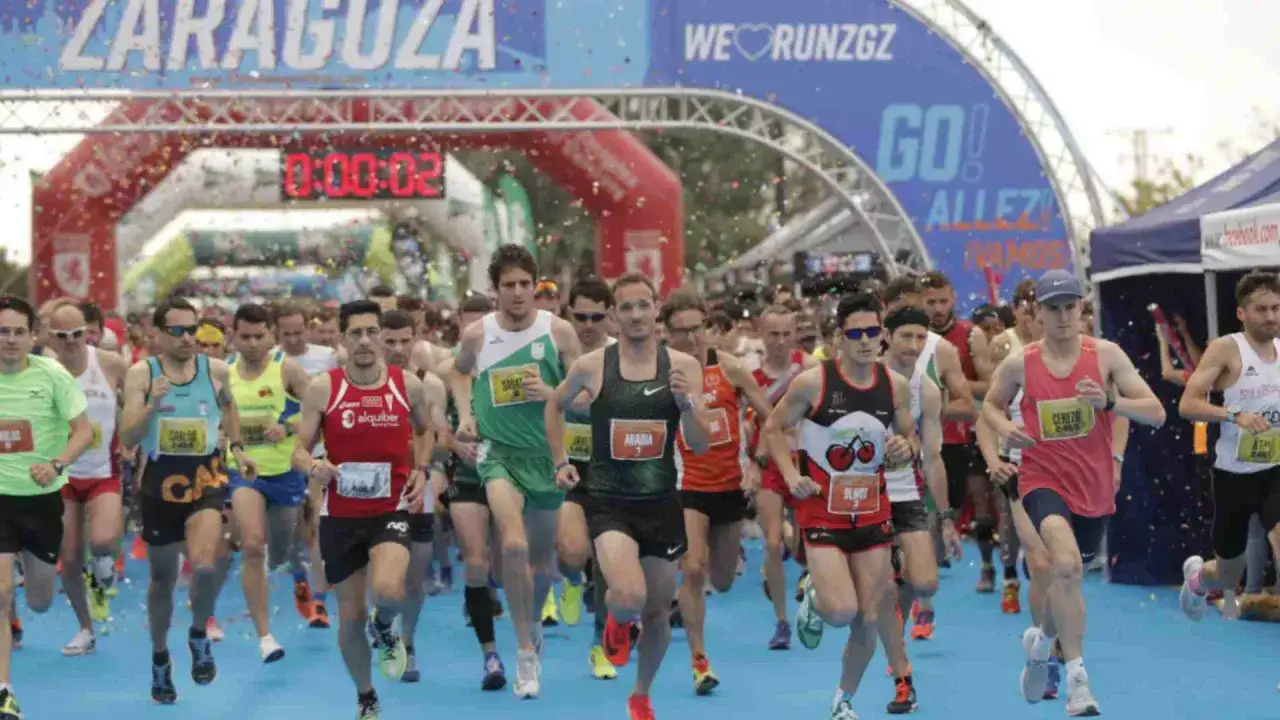 Corredores inician una de las carreras populares de Zaragoza, con confeti cayendo y el cronómetro marcando 0:00:02.
