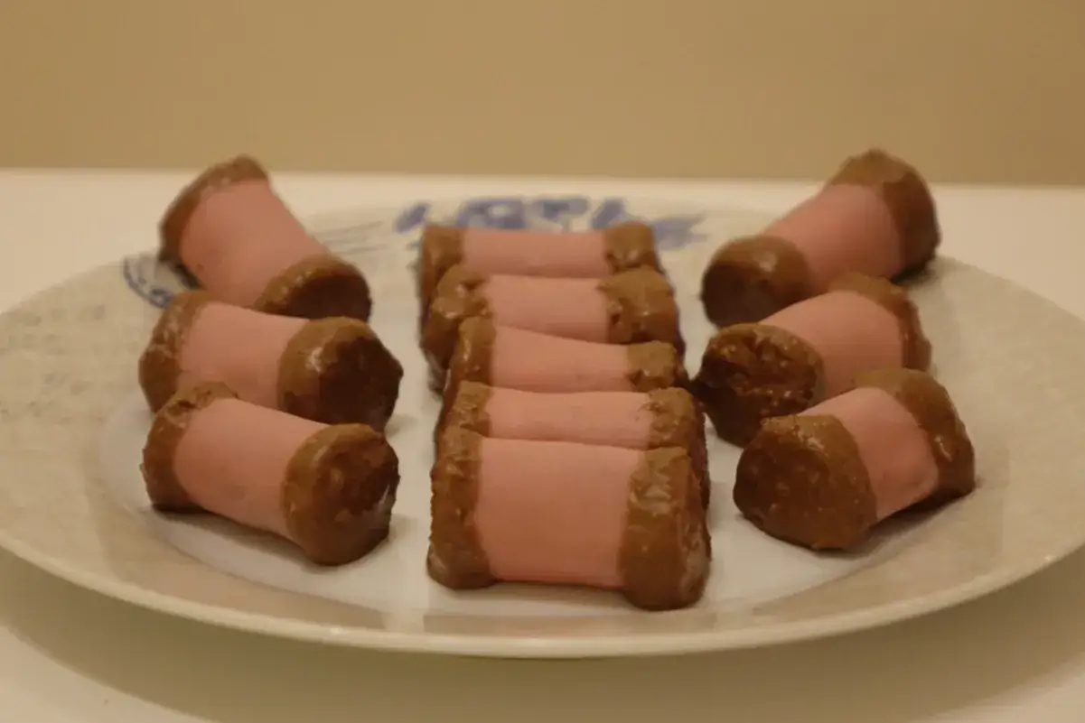 En tallrik med rosa punschrullar med chokladkanter. Perfekt f&ouml;r ett fika eller n&auml;r du vill baka ett klassiskt punschrulle recept.