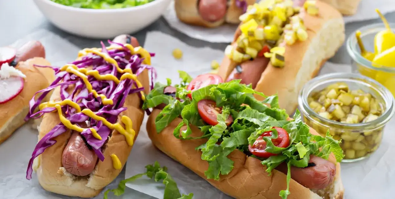 Leckere Hot Dogs mit Rotkohl, Senf, Salat und Tomaten. Die frischen Hot Dog Zutaten laden zum Genießen ein.