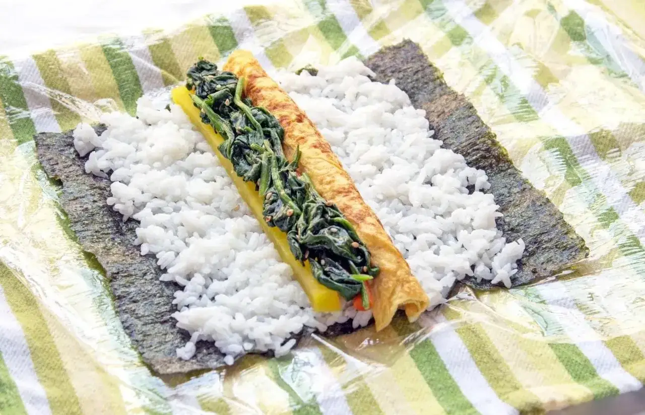 F&ouml;rberedelser f&ouml;r ett l&auml;ckert sushi recept: ris, nori, &auml;gg och spenat ligger redo att rullas.