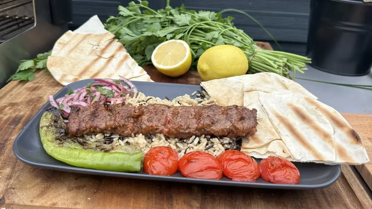 Adana Kebap Rezept: Saftiger Hackfleischspieß auf Reis mit gegrilltem Gemüse, Fladenbrot und Zitrone. Perfekt für den Grill!