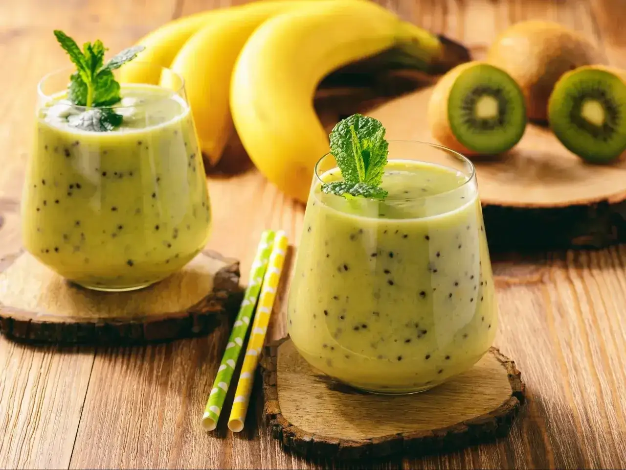 Dwa pyszne koktajle na przytycie z kiwi i bananem, ozdobione miętą. Idealne na zdrowy posiłek.
