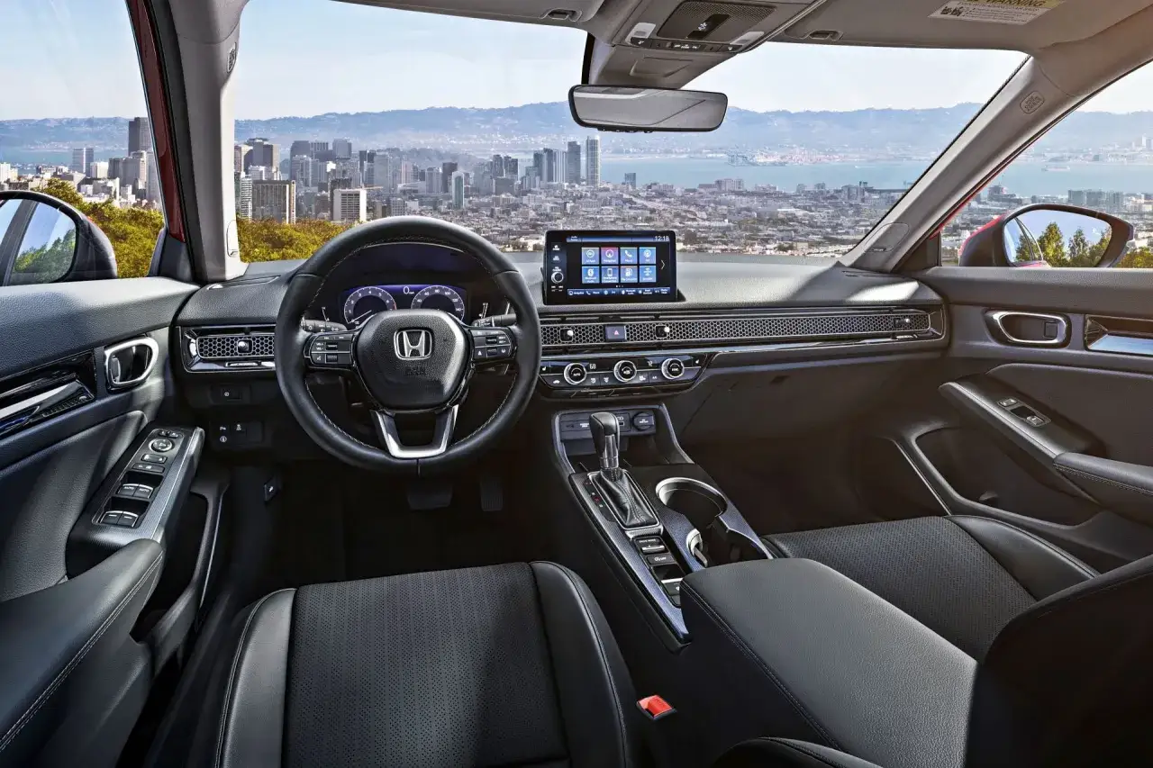 Wnętrze nowoczesnego **Honda Civic 11** z widokiem na panoramę miasta. Skórzana tapicerka, duży ekran dotykowy i kierownica z przyciskami.