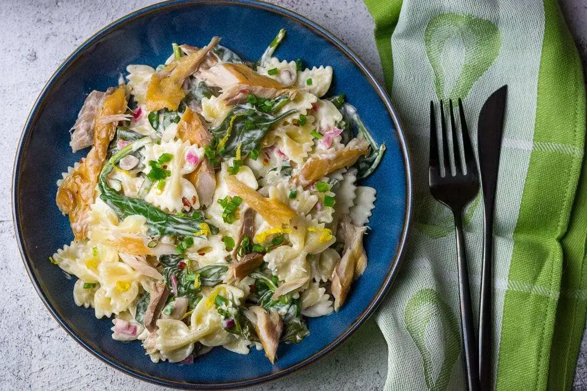 Pyszna pasta z makreli w sosie śmietanowym z dodatkiem szpinaku i ziół, podana na talerzu w kształcie motylków.