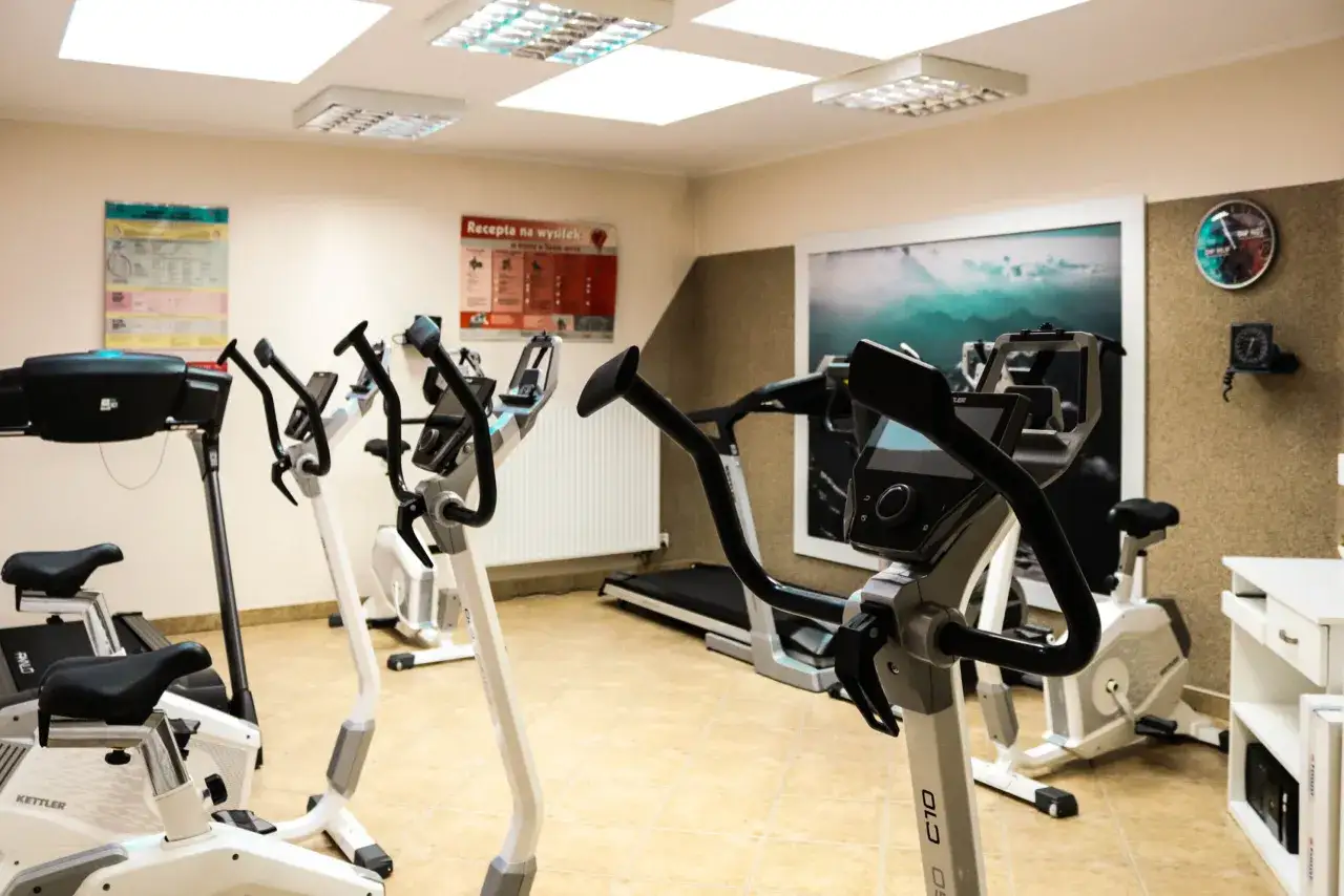 Sala do ćwiczeń z bieżnią i rowerkami stacjonarnymi, idealna do rehabilitacji po bajpasach.