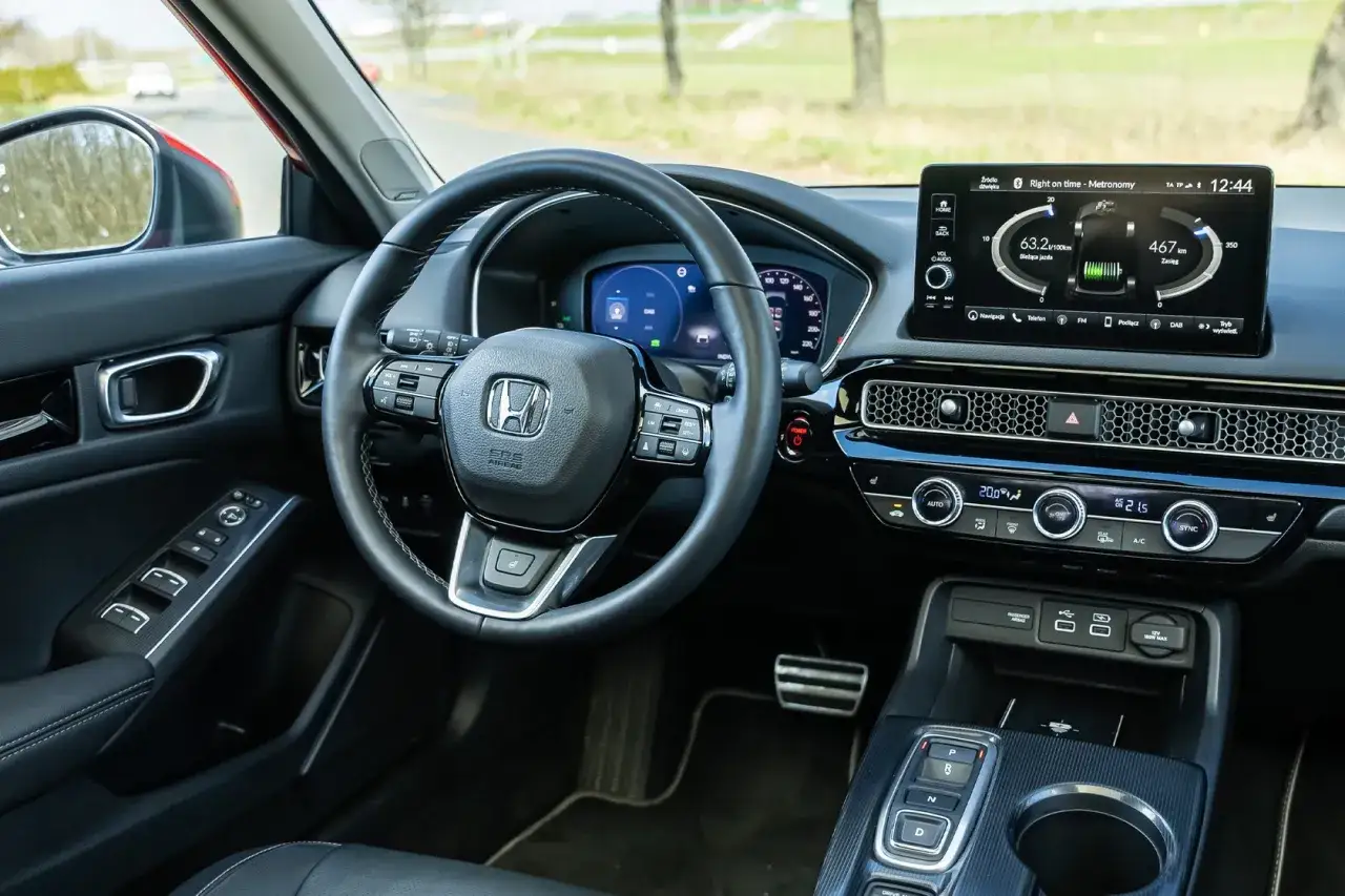 Wnętrze nowoczesnego **Honda Civic 11** z ekranem multimediów, cyfrowymi zegarami i kierownicą.