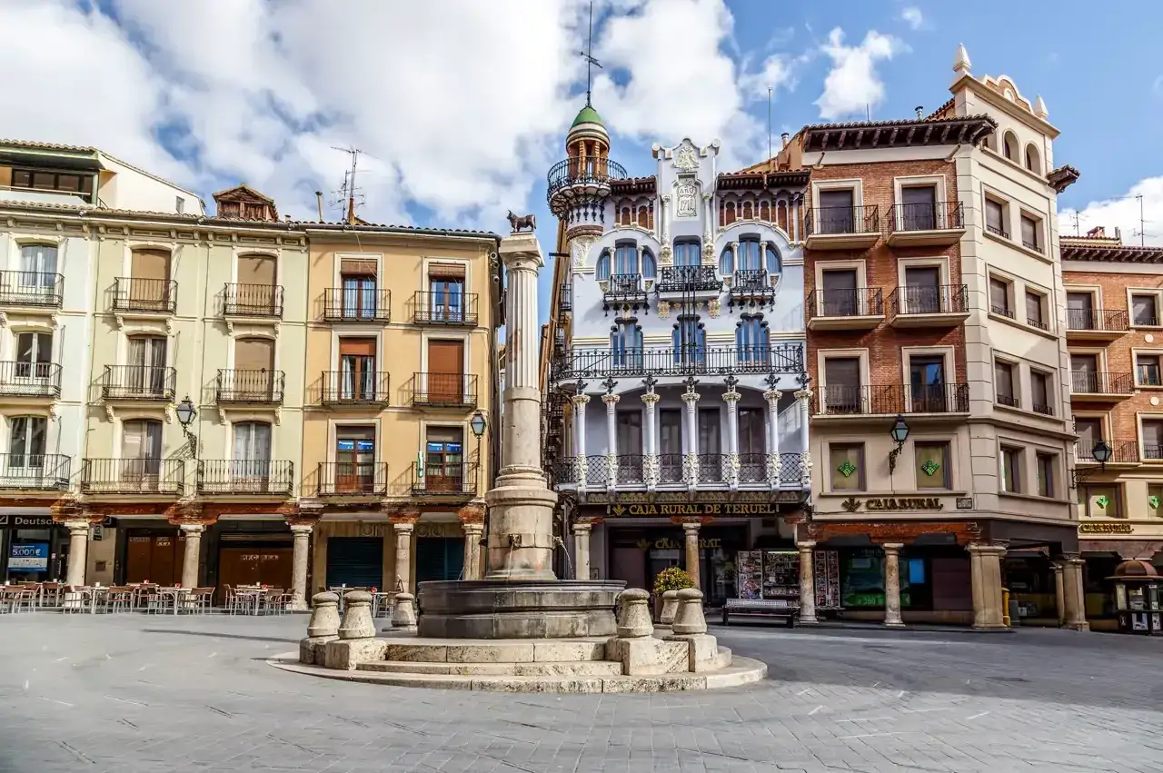 Plaza con fuente y edificios modernistas. Merece la pena visitar Teruel por su arquitectura &uacute;nica.