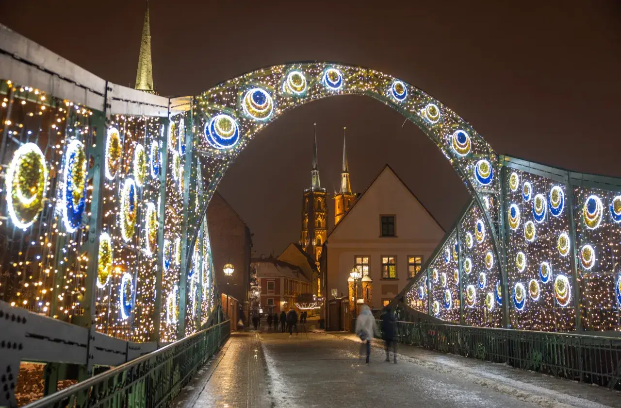 Mostek Tumski we Wrocławiu ozdobiony świątecznymi iluminacjami, tworząc magiczną atmosferę. Wrocław atrakcje zimą zachwycają!