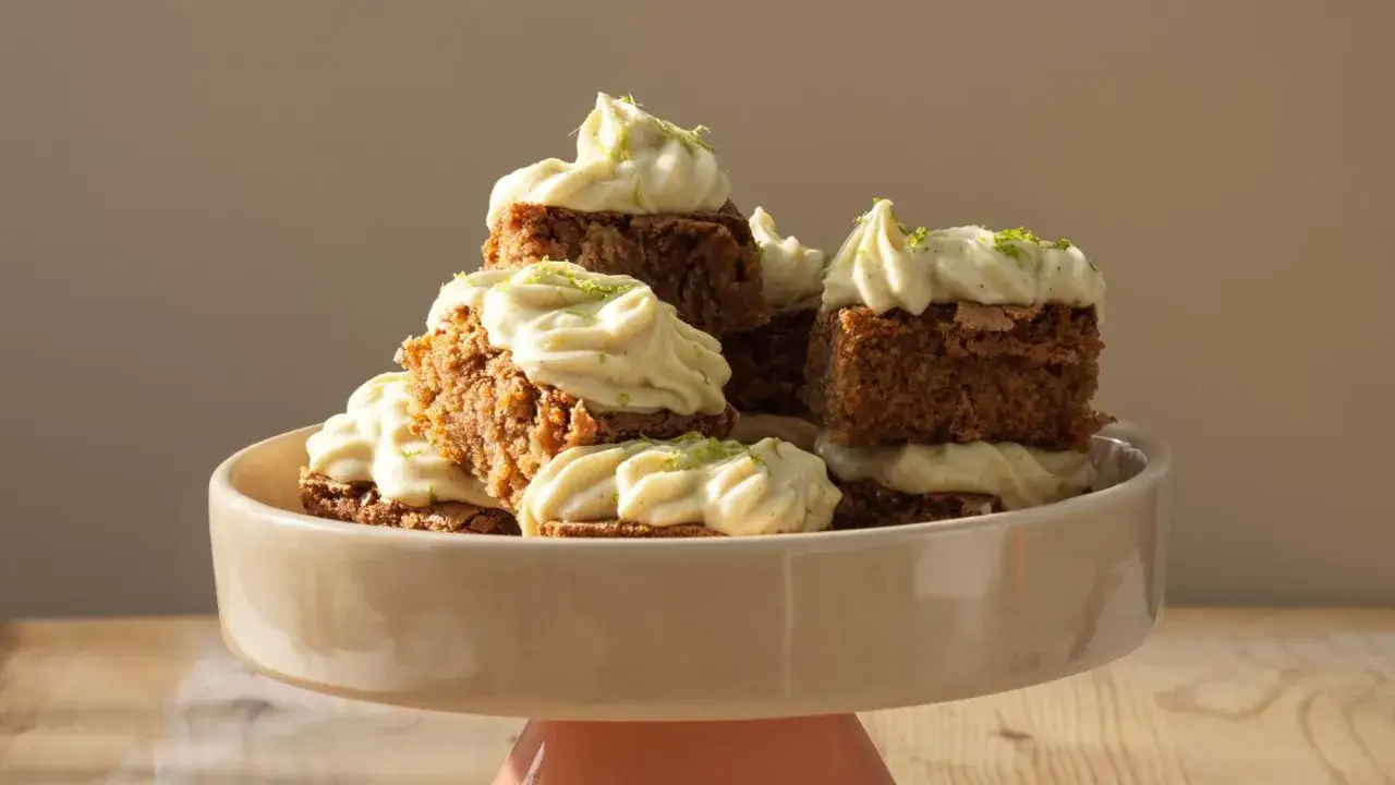 En hög med saftig morotskaka med smör istället för olja, toppad med krämig frosting och rivet limeskal.