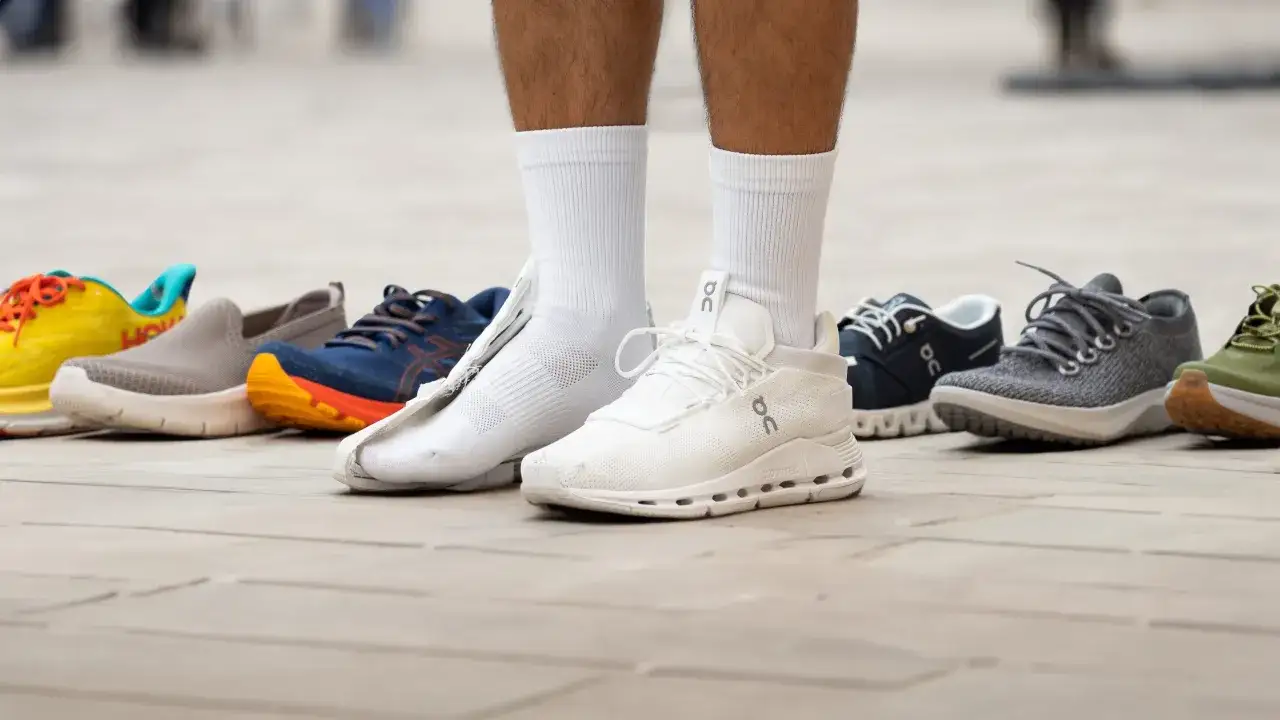 Un uomo sceglie tra diverse scarpe da ginnastica colorate, pronte per camminare in citt&agrave;.