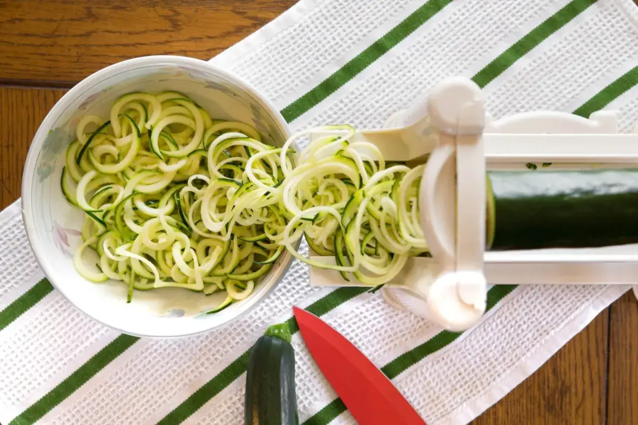 Zoodles rezept: Frische Zucchini-Nudeln werden mit einem Spiralschneider hergestellt und in einer Schüssel gesammelt.