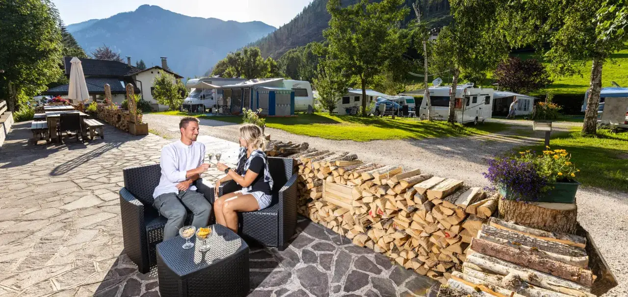 Coppia brinda al **camping Valle Verde** tra camper e montagne.