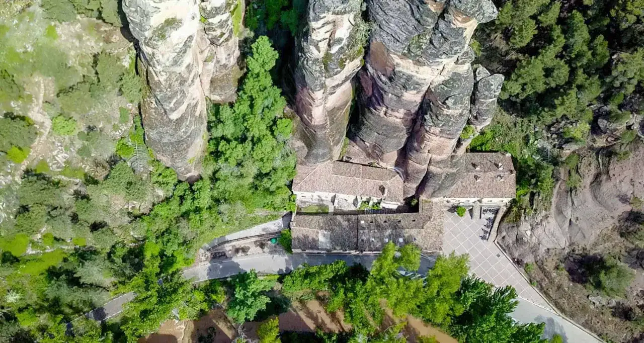 Edificio histórico en la ruta del barranco de la Hoz, rodeado de imponentes rocas y vegetación.