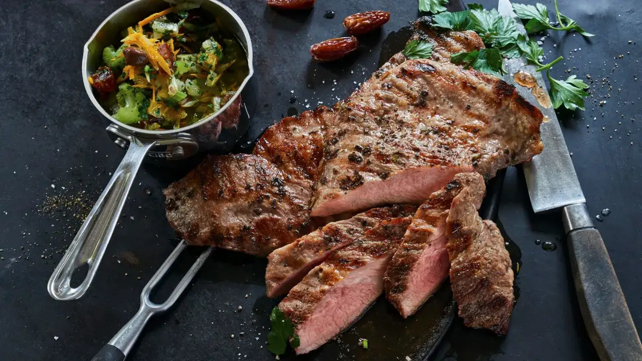 El secreto de cerdo a la parrilla, jugoso y tierno, acompañado de una guarnición fresca y dátiles.