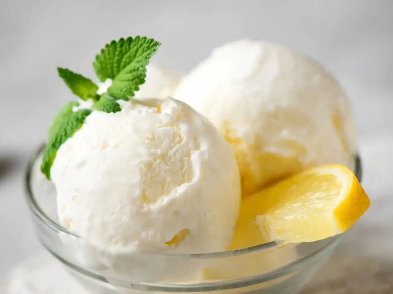 Delicioso helado de lim&oacute;n casero, servido en un cuenco de cristal con hojas de menta y rodajas de lim&oacute;n fresco.