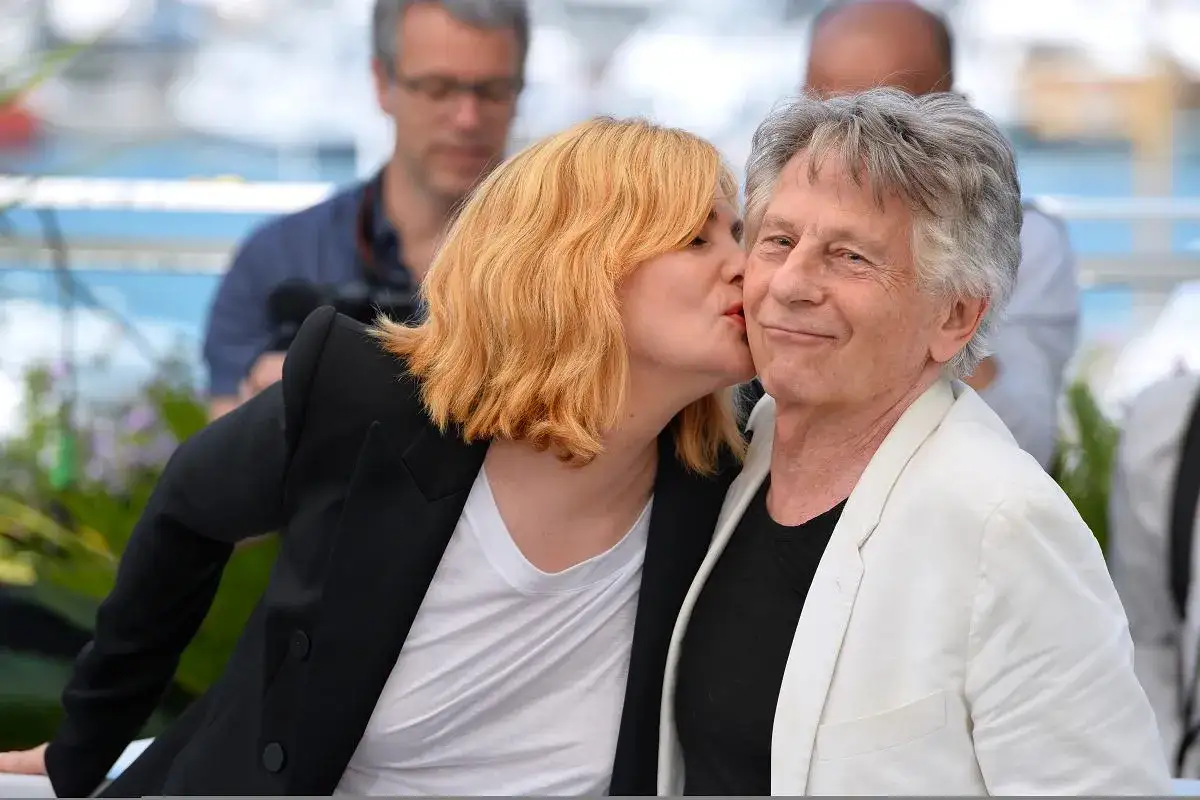 Emmanuelle Seigner całuje Romana Polańskiego. W tle widać fotografa.