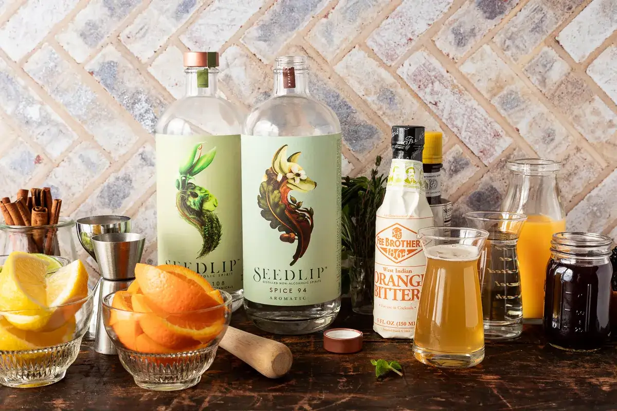 Zutaten für alkoholfreie Cocktails: Seedlip-Flaschen, Orangen- und Zitronenspalten, Zimtstangen, Saft und Bitter.