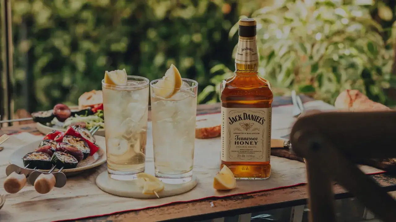 Letni wieczór z przyjaciółmi i orzeźwiający drink z Jack Daniel's miodowy. Na stole grillowane warzywa i świeże pieczywo.