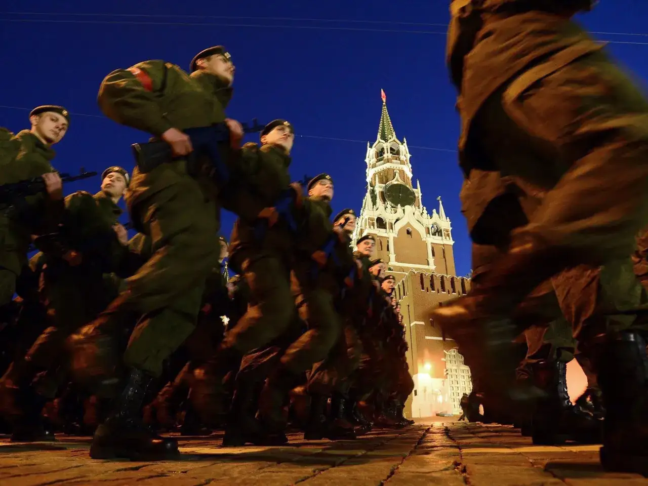 Soldaten marschieren im Dunkeln über den Roten Platz. Der Kreml ist im Hintergrund zu sehen. Ein feierlicher Anblick am 8. Mai, dem Feiertag in Russland.