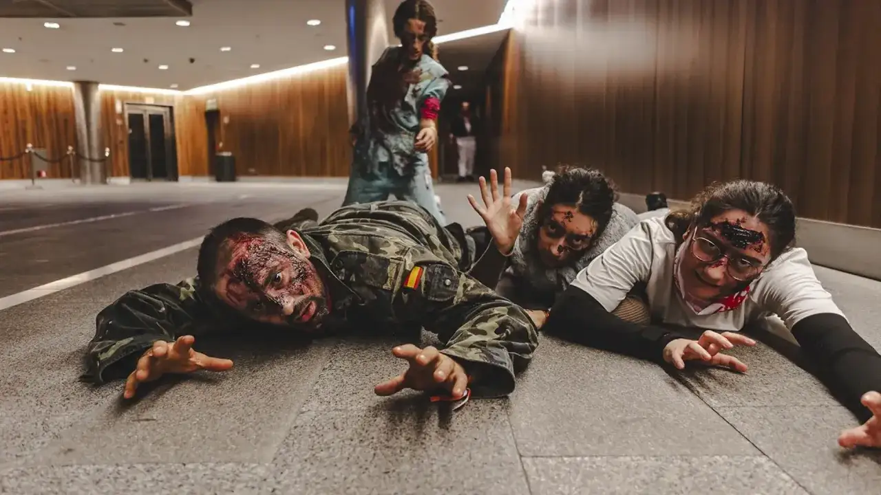 Zombis arrastrándose en Puerto Venecia Halloween, con maquillaje de heridas y sangre.