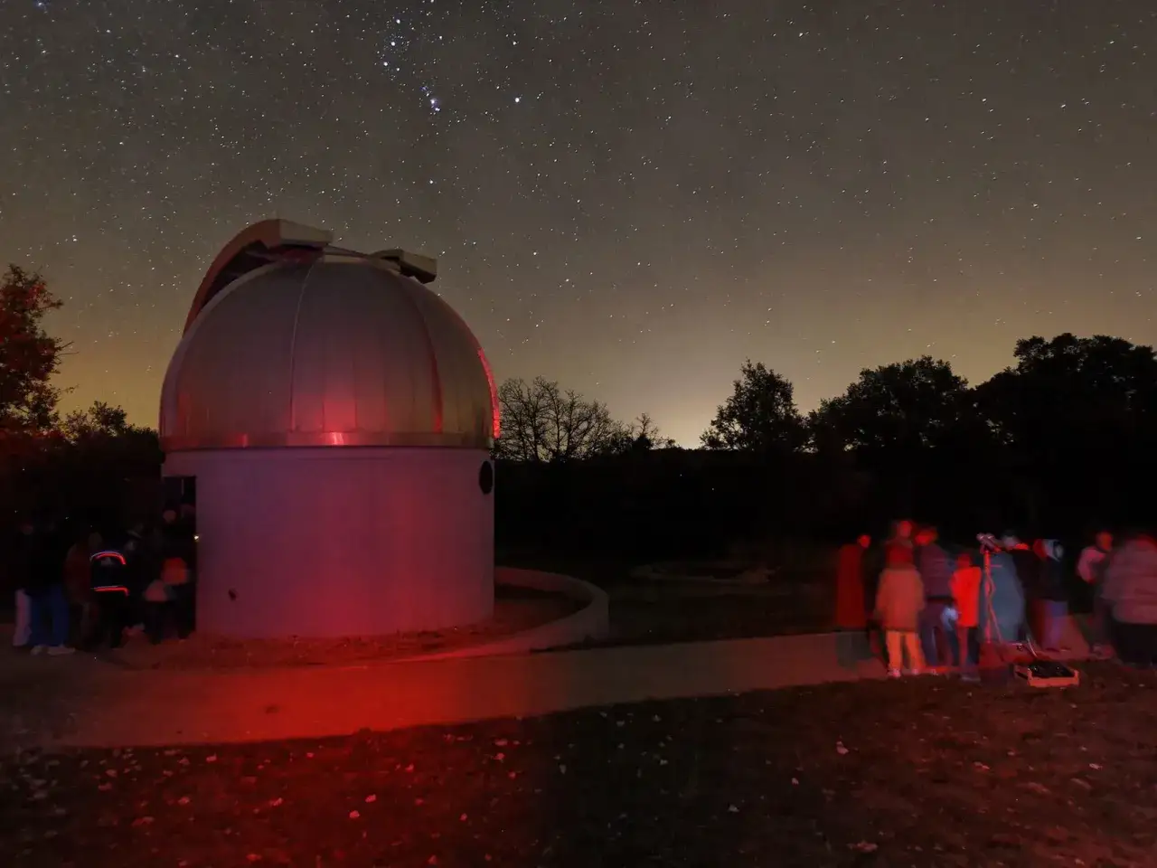 Nuit &eacute;toil&eacute;e au saint michel l'observatoire. Un d&ocirc;me d'astronomie baign&eacute; de lumi&egrave;re rouge, entour&eacute; d'une foule curieuse observant le ciel.