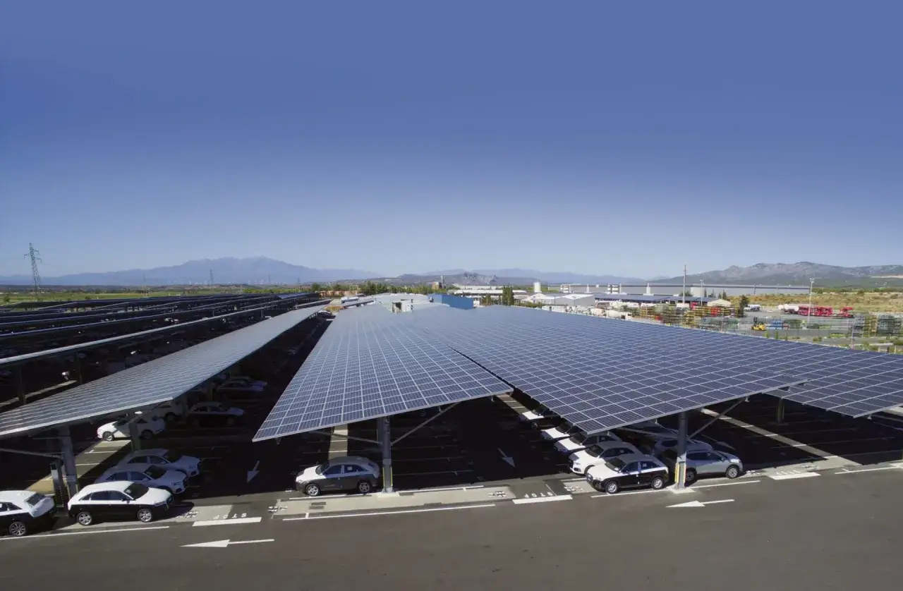 Vaste parking ombragé par une centrale panneau solaire. Des voitures sont garées sous les panneaux, profitant de l'ombre et de l'énergie verte.
