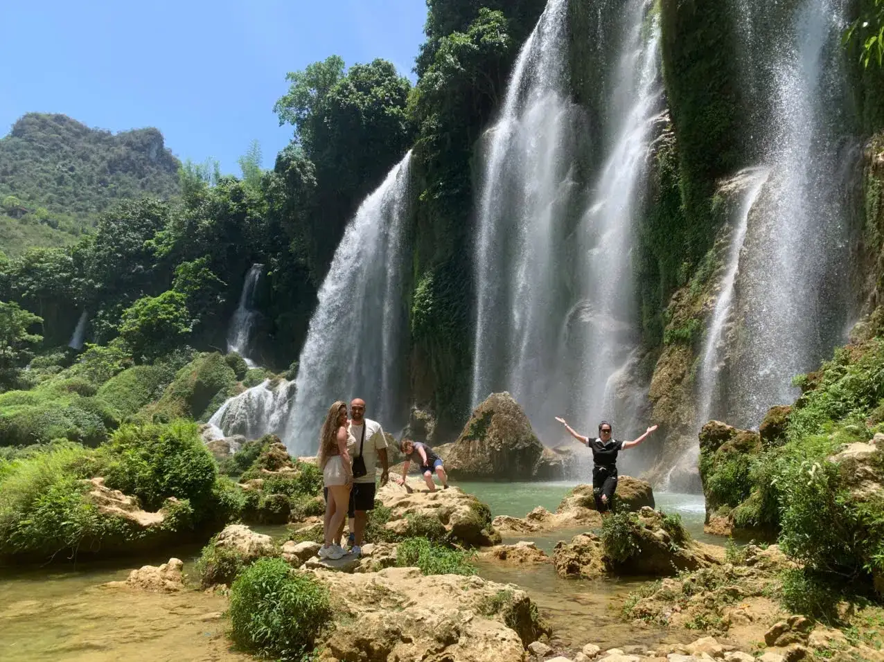Ein Paar genießt die atemberaubende Kulisse der Ban Gioc Wasserfälle, ein perfekter Ort für eine **Nordvietnam Reisezeit**.