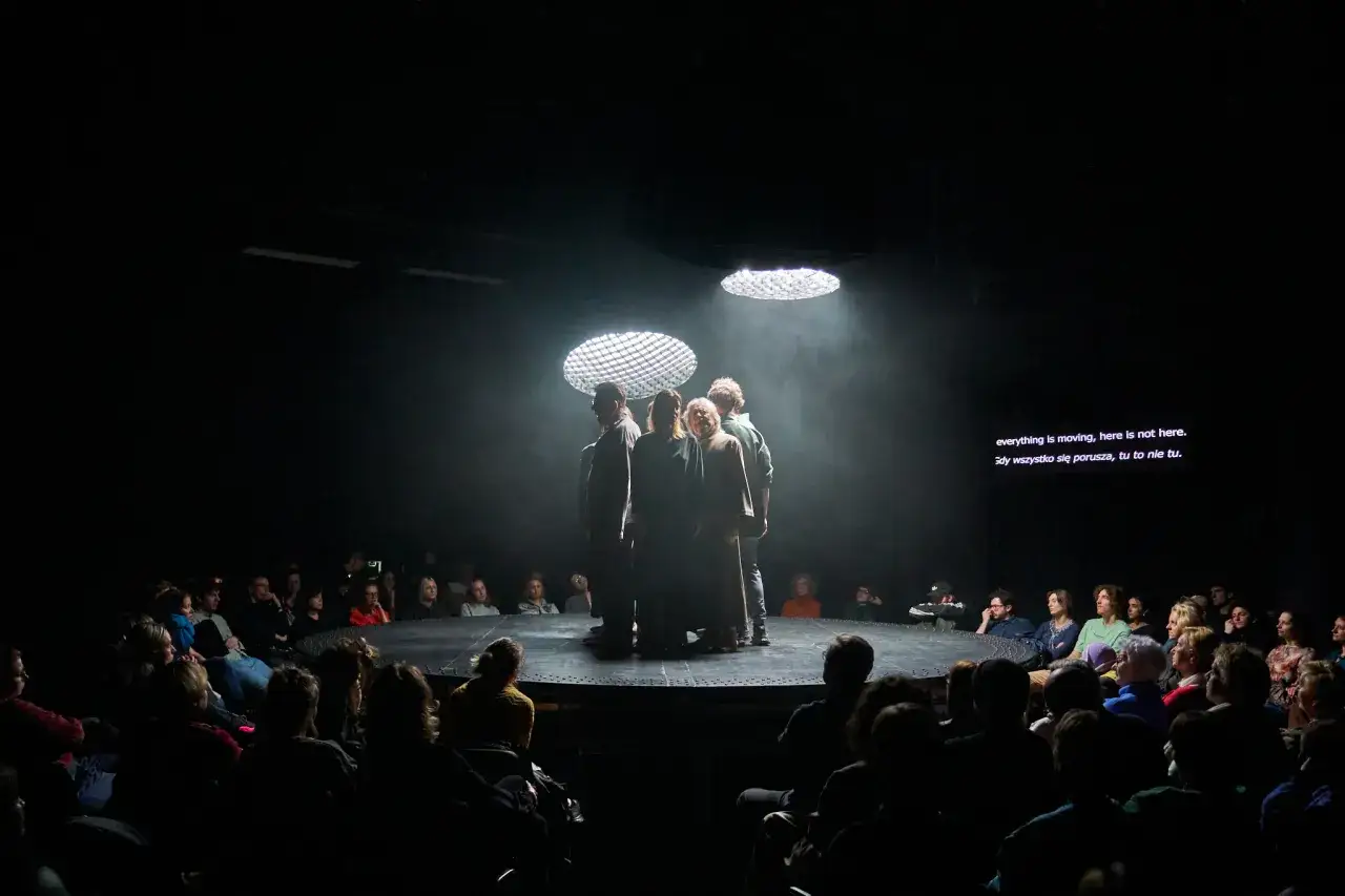 Aktorzy na scenie w teatrze w Warszawie, w dymie i świetle. Widownia wpatrzona w spektakl.