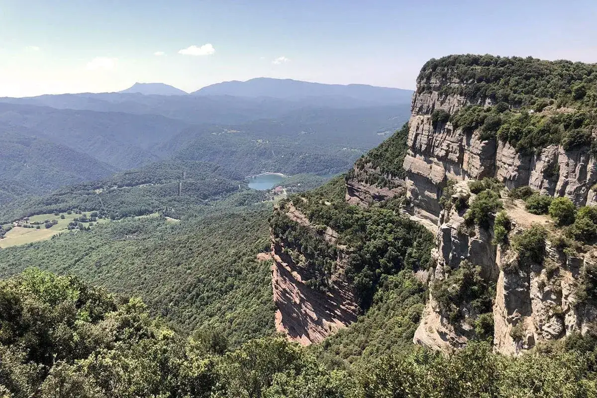 Beeindruckende Barcelona Natur: Steile Felsw&auml;nde und gr&uuml;ne T&auml;ler mit einem See in der Ferne.