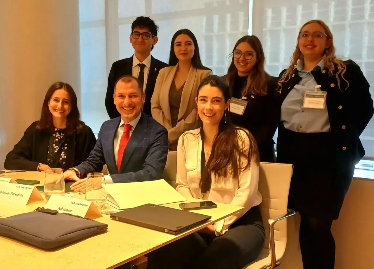 Grupo de jóvenes profesionales sonríe en una sala de reuniones, preparándose para una carrera en derecho internacional.