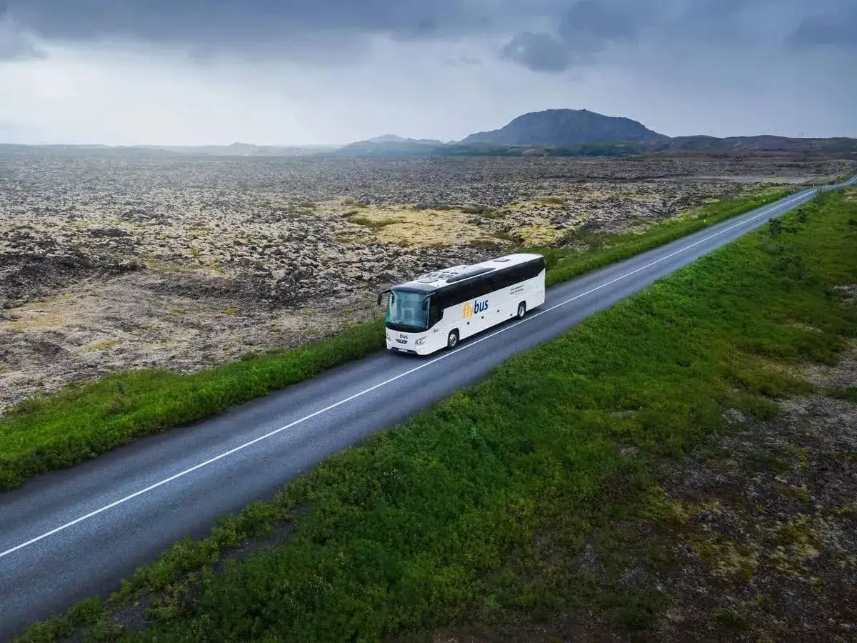Autobus Flybus jedzie pustą drogą przez islandzki krajobraz wulkaniczny w kierunku lotniska Keflavik.