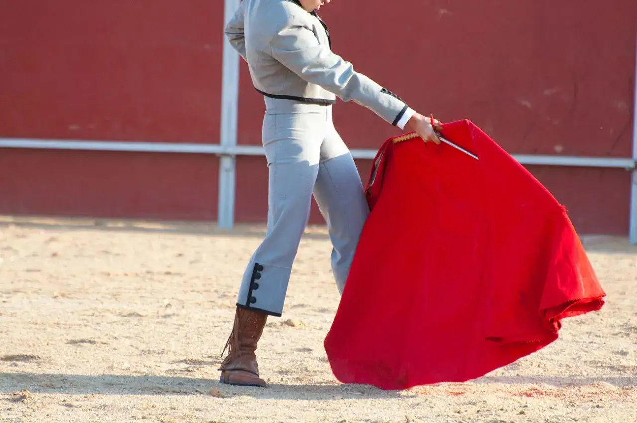 Un torero realiza una faena de muleta, con la tela roja ondeando en la arena.