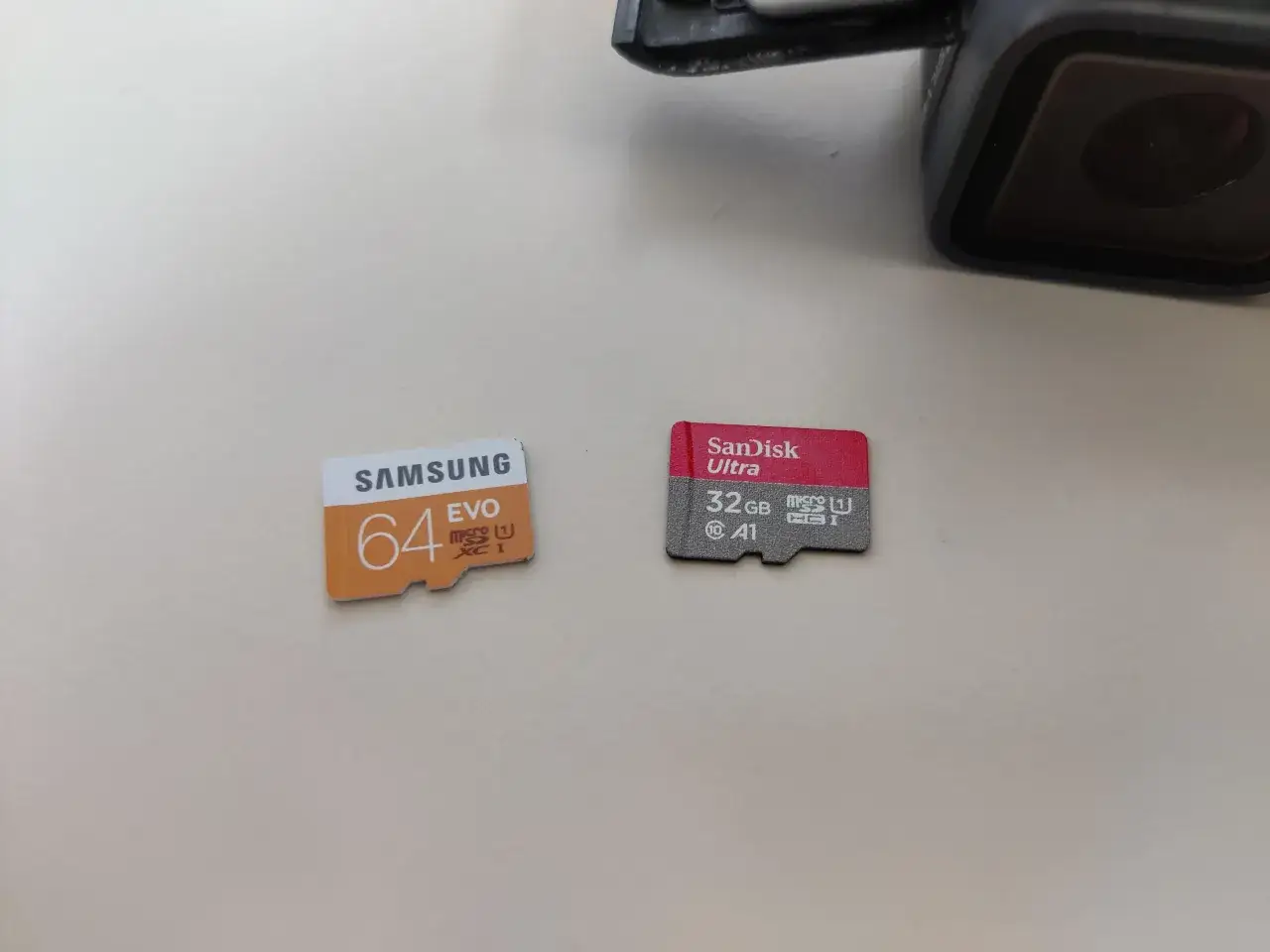 Zwei Micro-SD-Karten, eine Samsung 64GB und eine SanDisk 32GB, liegen neben einer GoPro. Bereit f&uuml;r das Formatieren der GoPro SD-Karte.
