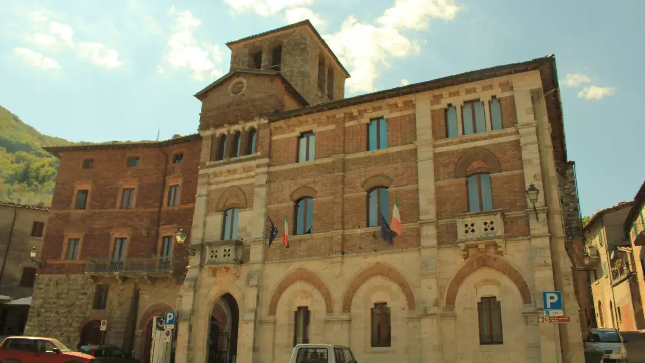 Edifici storici a Montieri, Grosseto, con bandiere italiane e un cielo azzurro.
