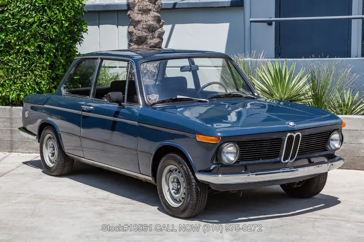 En blå BMW 70-tals coupé står parkerad utomhus.