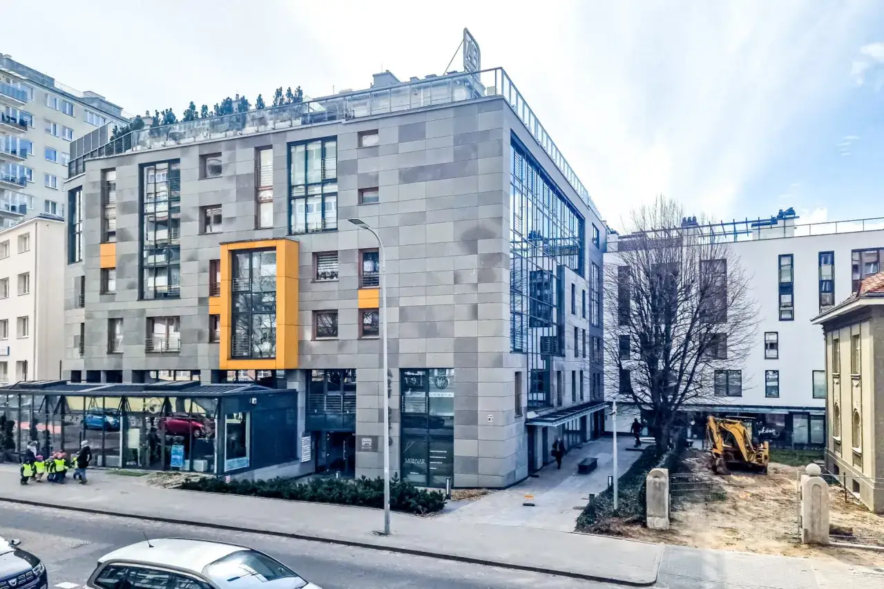 Nowoczesna architektura w stylu art deco w Polsce. Budynek z szarymi płytami, przeszklonymi fasadami i żółtymi akcentami.