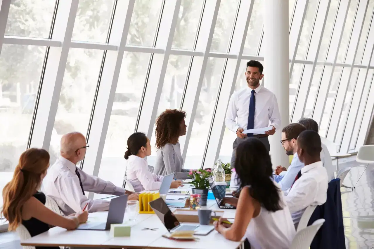 A diverse group of professionals engage in effective board meetings, with a presenter leading the discussion in a modern conference room.