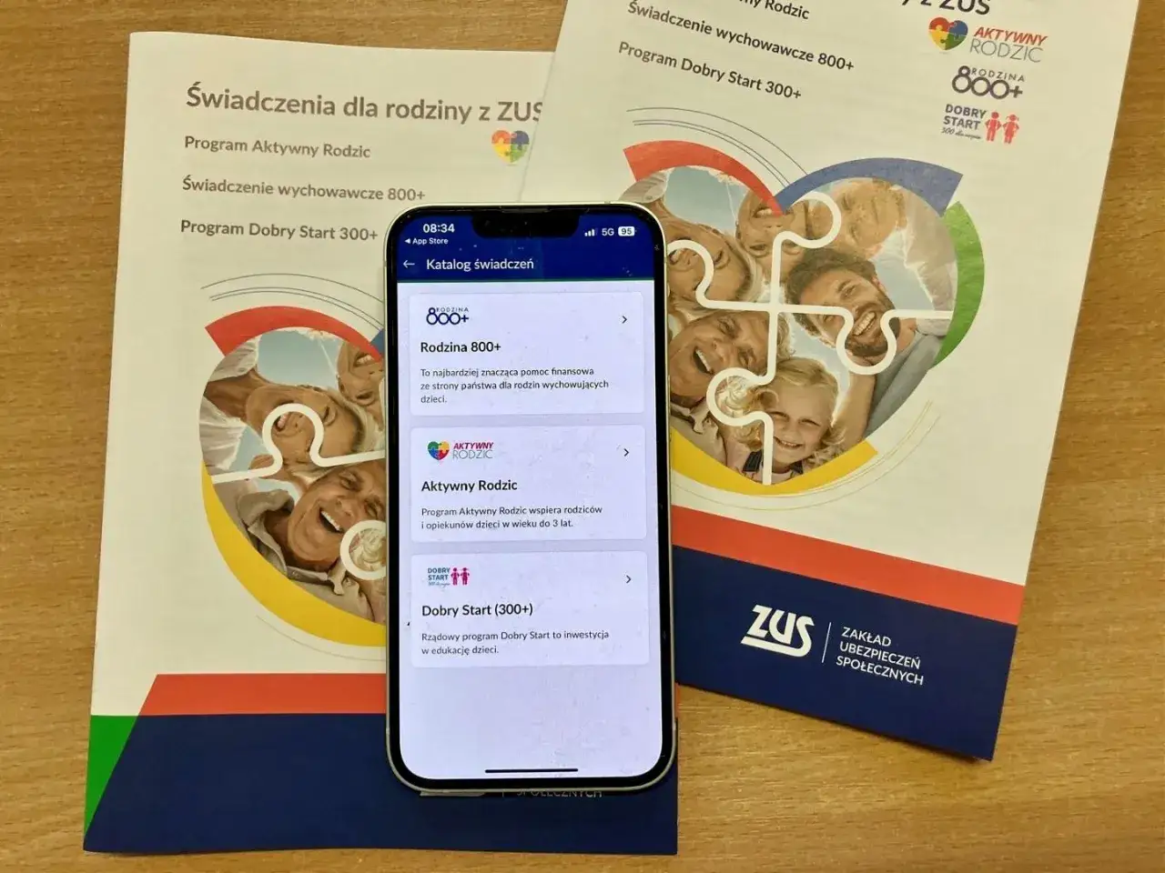 Program Dobry Start 300+ to wsparcie dla edukacji dzieci. Na ekranie telefonu widać katalog świadczeń ZUS, w tym Rodzina 800+ i Aktywny Rodzic.