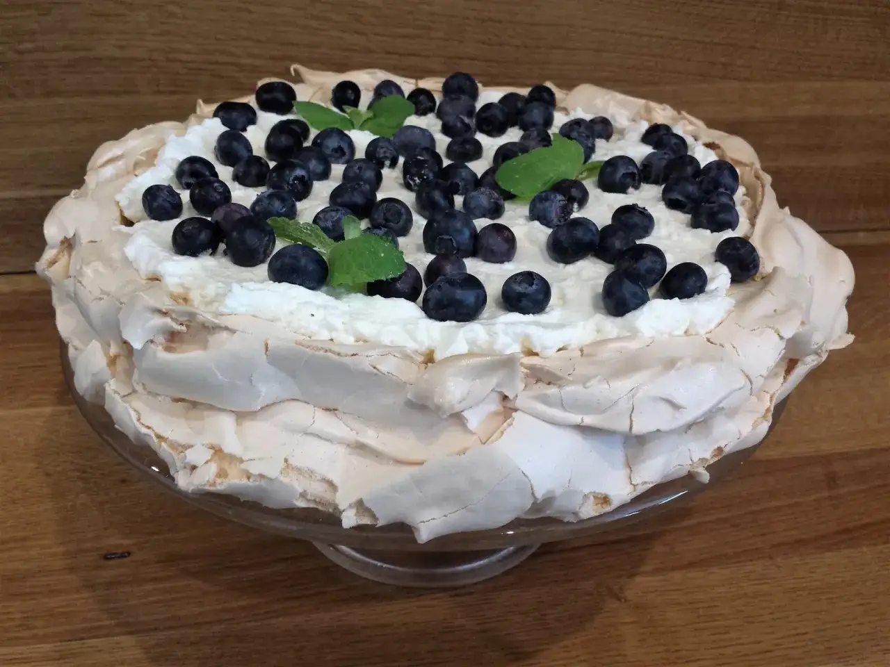 Pyszny tort bezowy z bitą śmietaną i bor&oacute;wkami. Czy tort bezowy można zrobić dzień wcześniej? Tak, ten wygląda idealnie!