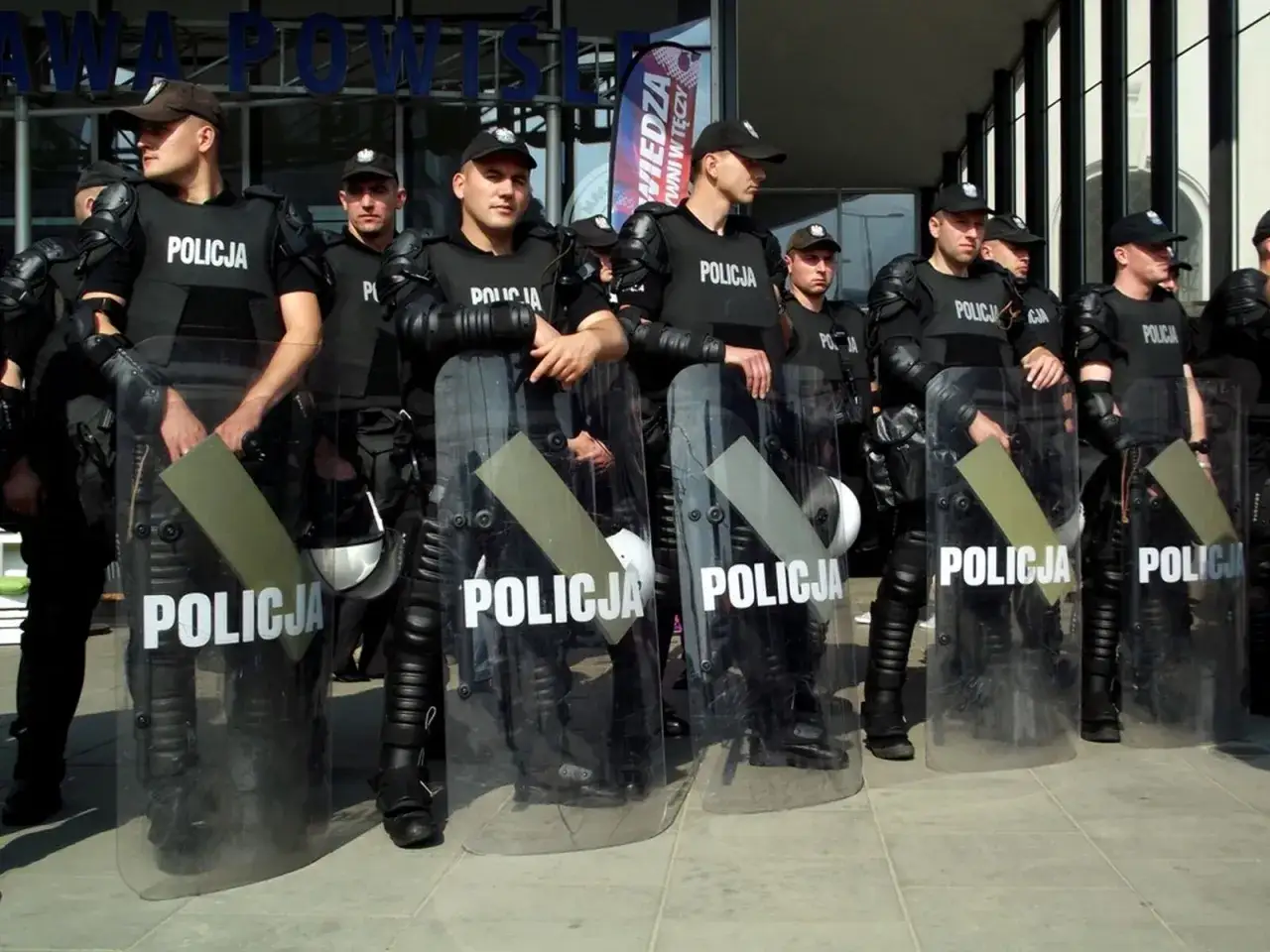 Policjanci w pełnym rynsztunku, z tarczami z napisem 