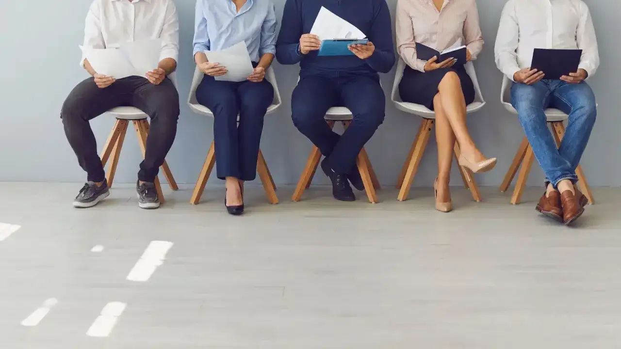 Cinq personnes assises, attendant un entretien. Leurs CV en main, ils esp&egrave;rent n&eacute;gocier un bon salaire, peut-&ecirc;tre pour un poste de chasseur de t&ecirc;te.
